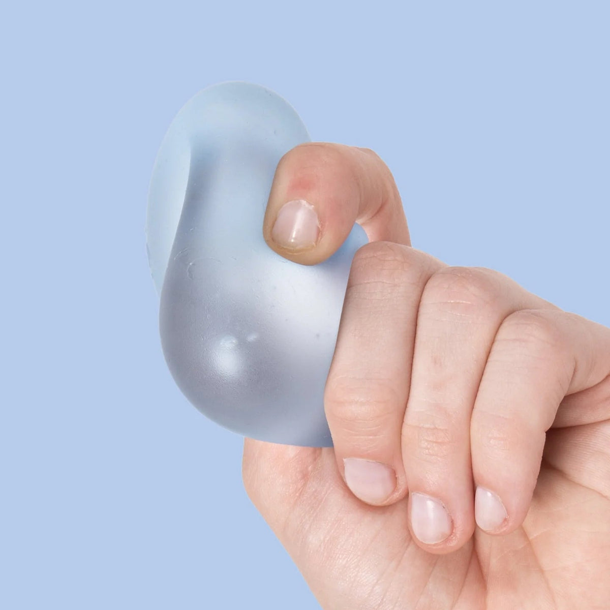 A hand squeezing a small, translucent, pear-shaped stress toy against a solid light blue background.