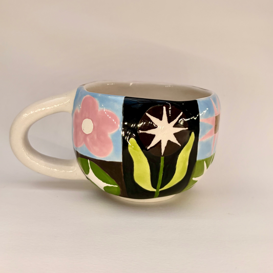 Ceramic mug with colorful floral and abstract design on a plain background