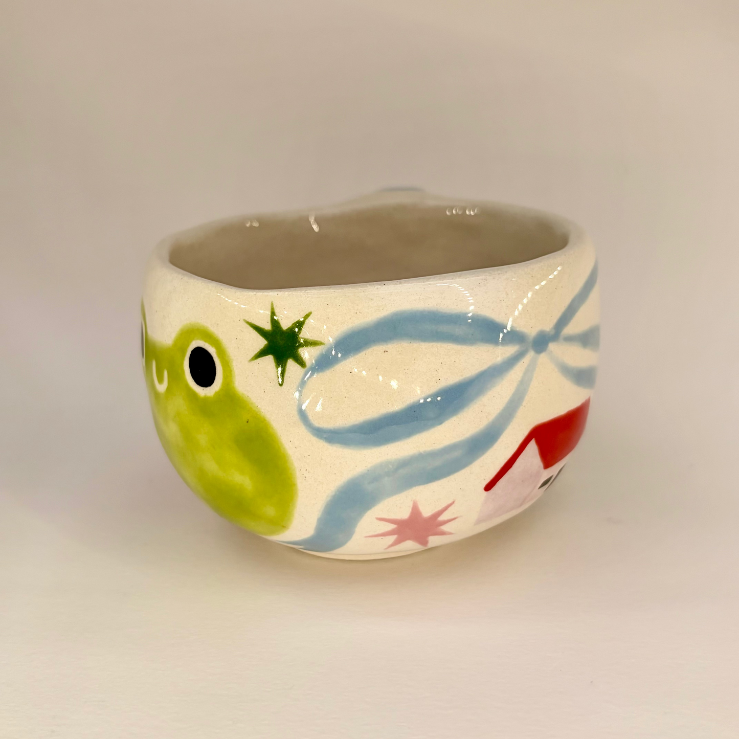 Ceramic mug with a frog design on a plain background