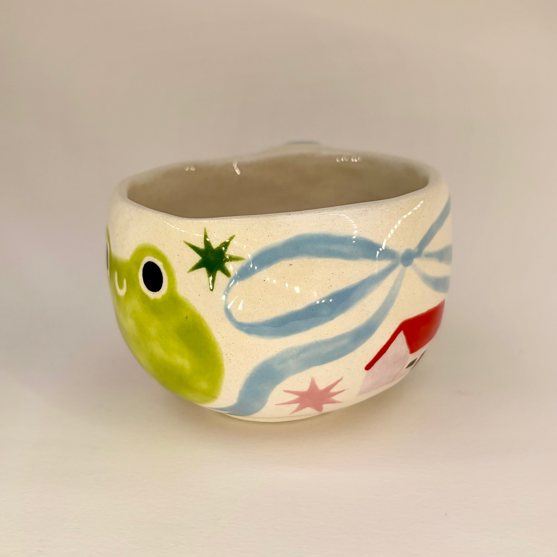 Ceramic mug with a frog design on a plain background