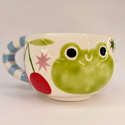 Ceramic mug with a frog design on a plain background