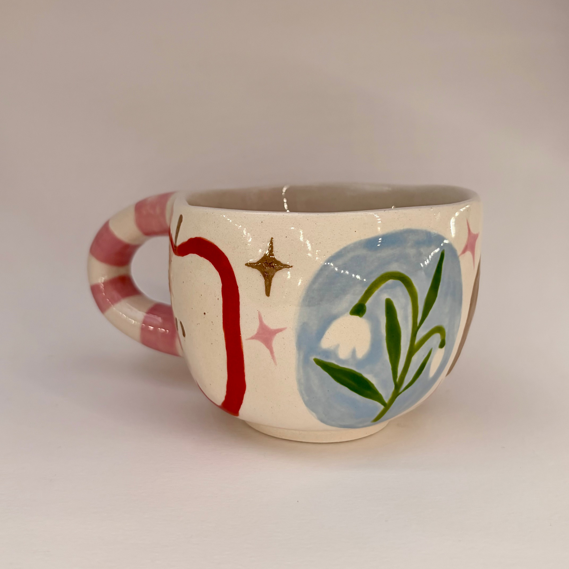 Ceramic mug with colorful designs on a plain background