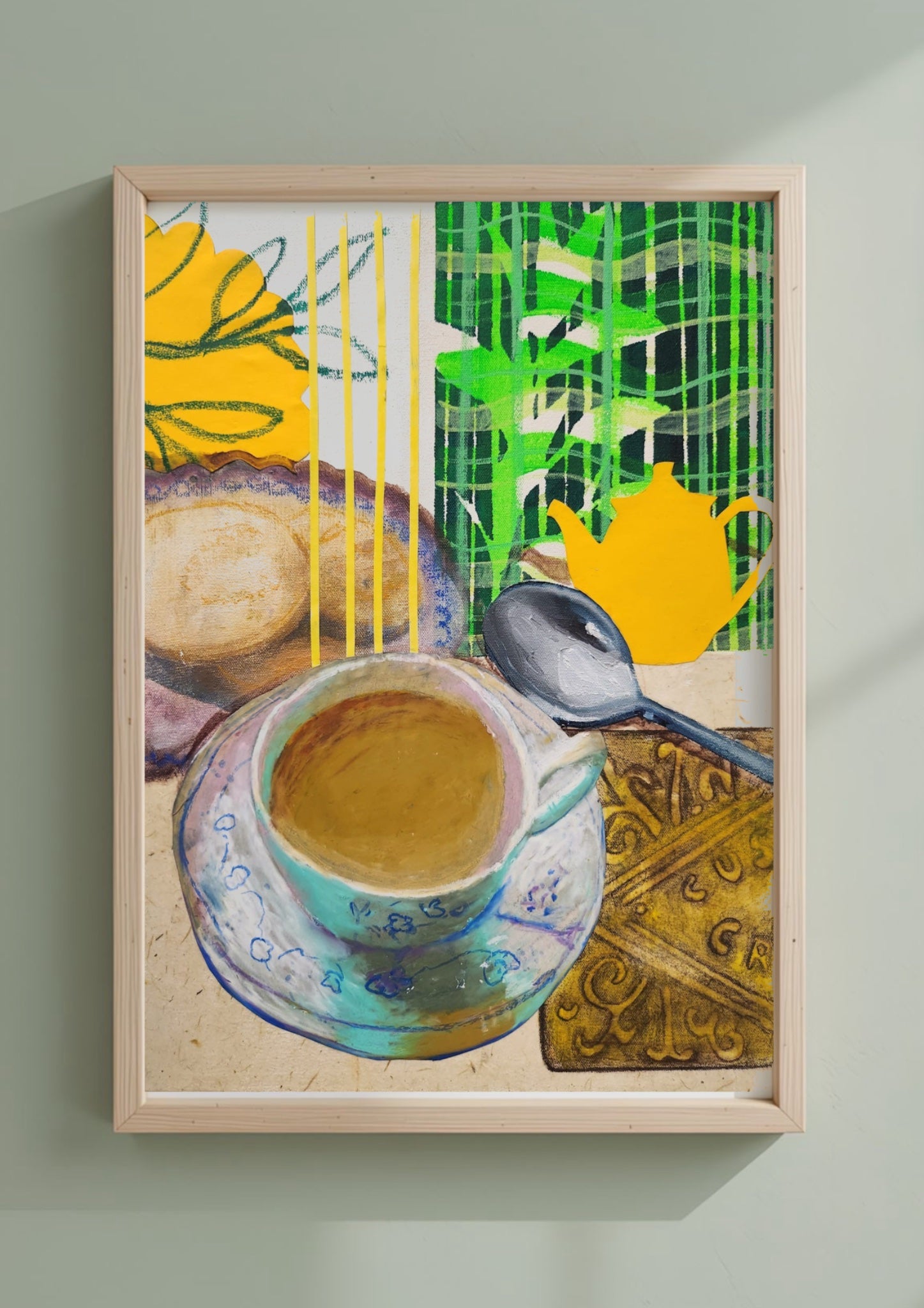 A framed art print featuring a colorful still life painting of a cup of tea, a spoon, a teapot, and abstract botanical elements, displayed on a light green wall.