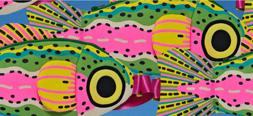 A close-up of two colorful fish-shaped cross body bag featuring a vibrant pattern of pink, green, yellow, and black rainbow trout fish on a blue background.