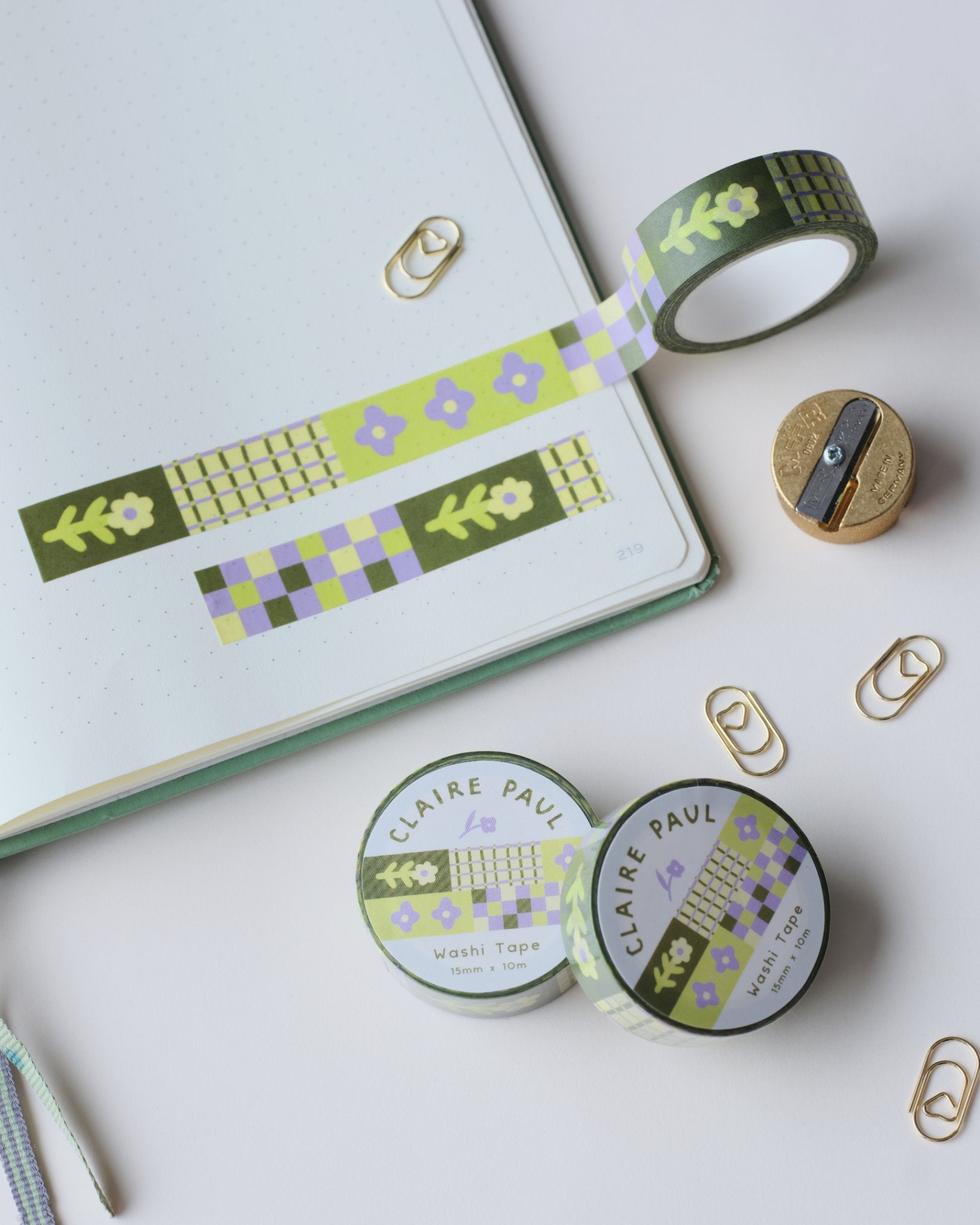 Washi tape with floral patterns, on a white surface featuring a sharpener and paperclips