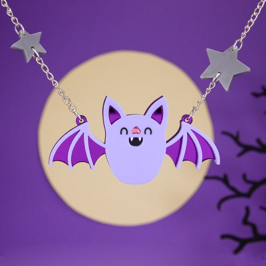 Necklace with a large cartoon bat pendant, and grey stars on the chain against a purple background