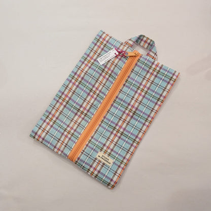 A folded plaid garment bag with a pastel multicolor pattern and a prominent orange zipper, shown on a plain light background with its tags attached.