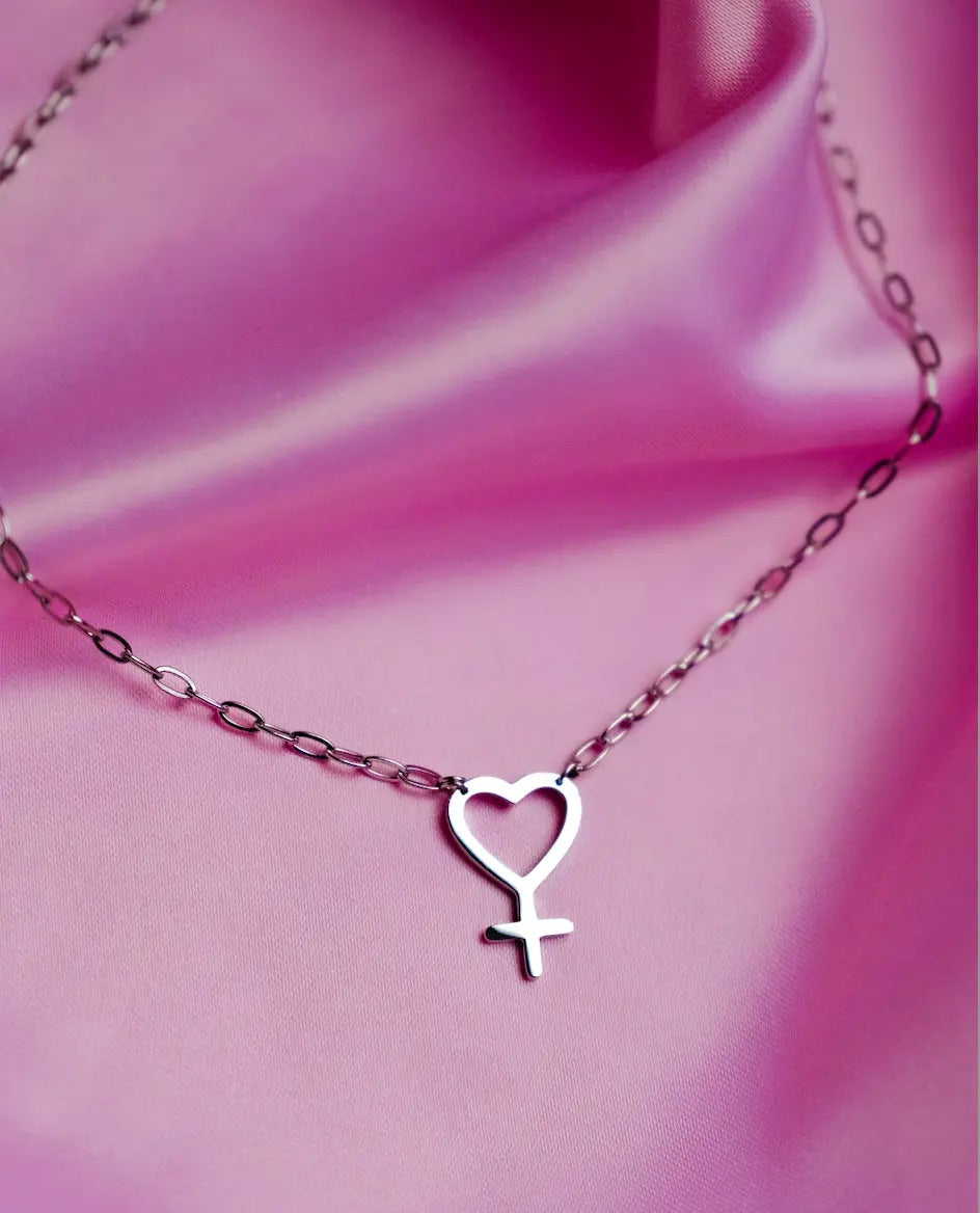 Necklace with a heart-shaped/venus symbol on a pink silky fabric background