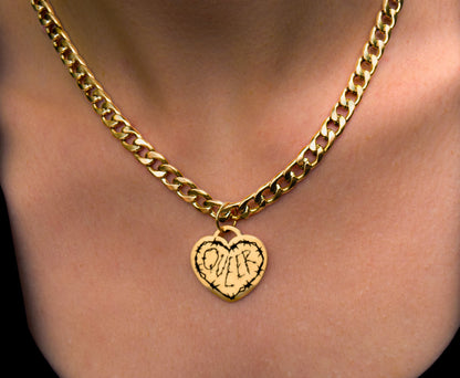 Gold chain necklace with a heart-shaped pendant on a person's neck