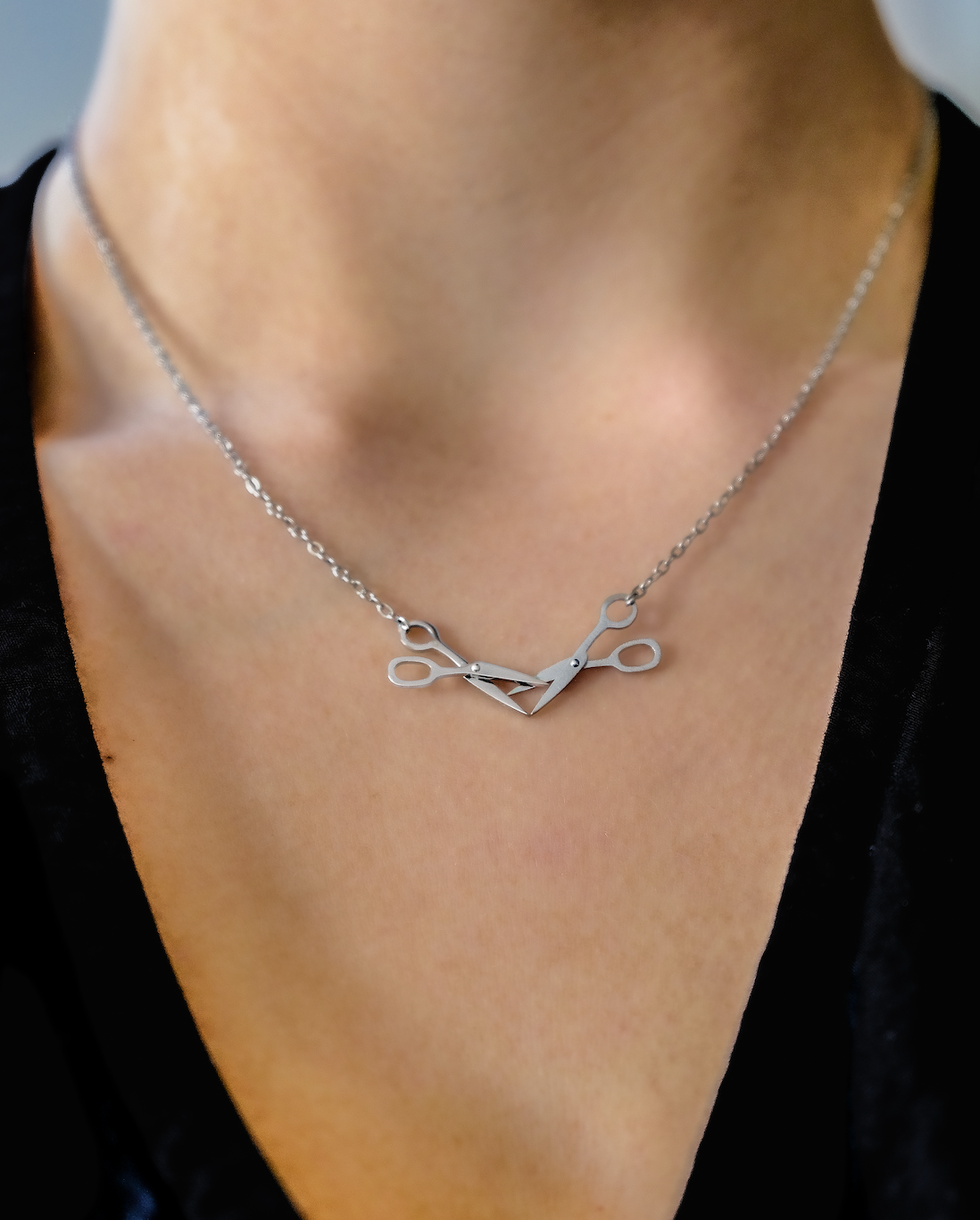 Silver scissors necklace on a person's neck