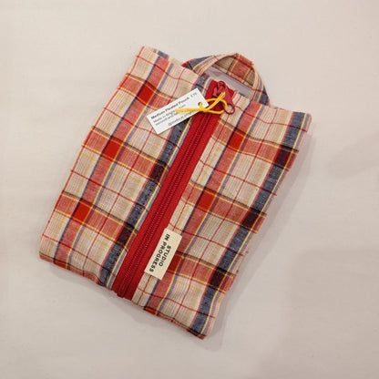 A folded plaid zippered pouch or small bag with a red zipper, shown on a plain light background. The fabric has a plaid pattern in red, blue, and beige, with a visible sewn label reading 'PERSIAN WAVE' and a hangtag attached.