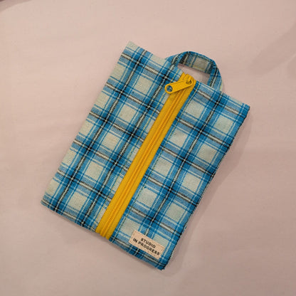 A blue and white plaid zippered pouch with a bright yellow zipper and handle, shown on a light pink background.